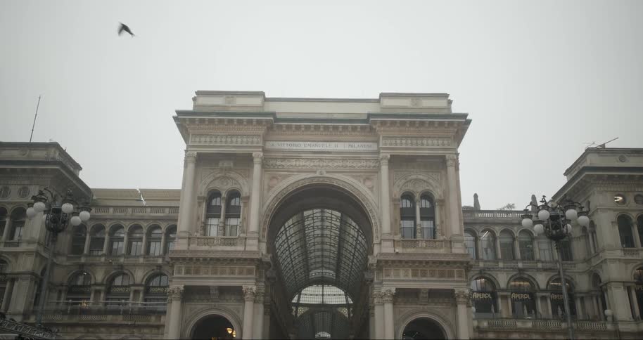 Facade of a classical building with a glass arch on a cloudy day