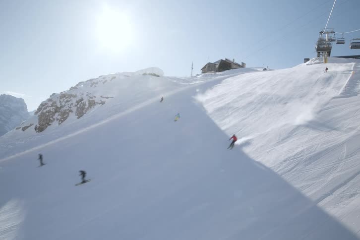 Skiers snow skiing down a slope on a bluebird day