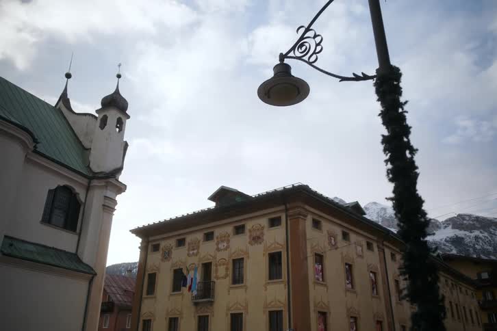 A lowangle shot shows a street lamp near and a church with a green roof against a cloudy sky