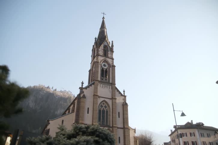 Classic church with an imposing tower and mountains in the background
