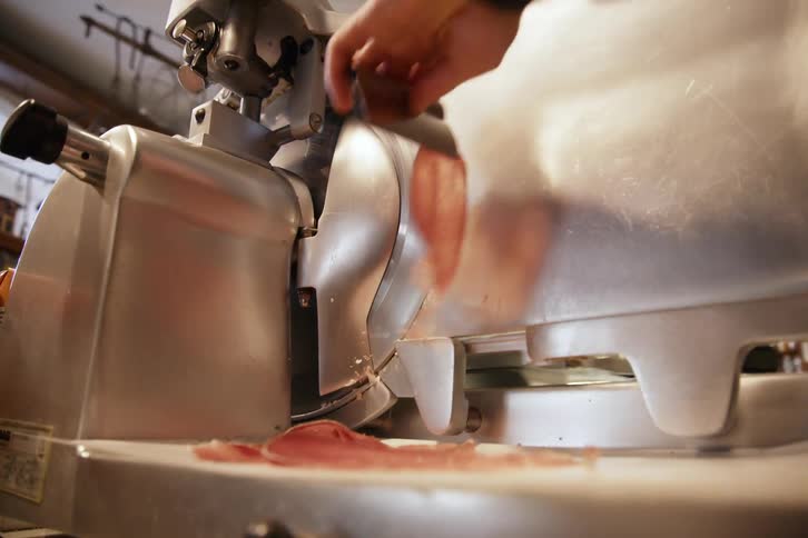 Hand removing thin fillets of meat cut by a machine