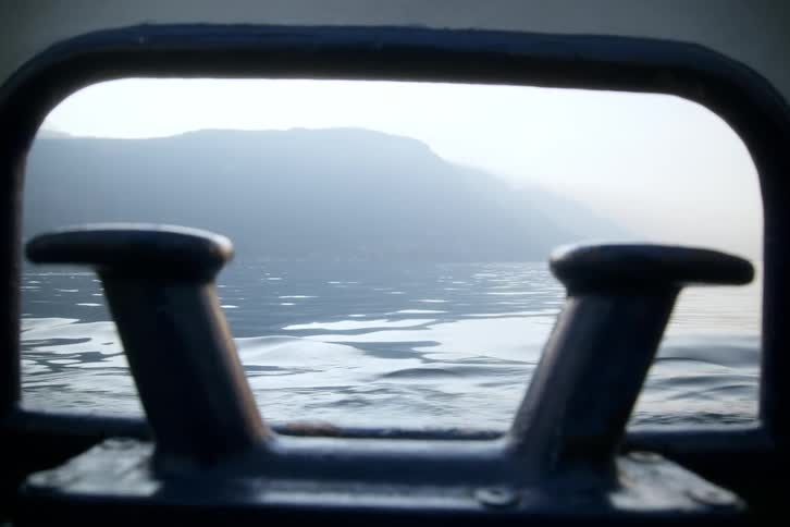 A view from a small window of a boat with two mental objects and a view of a lake