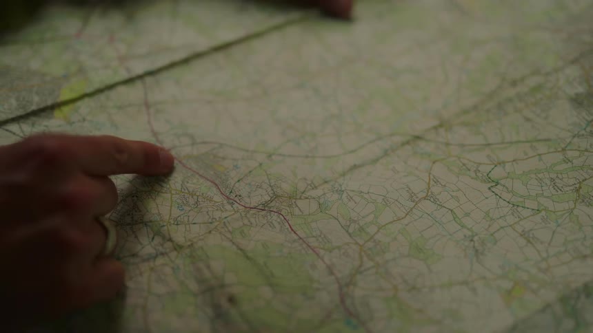 Person traces a route on an unfolded paper map