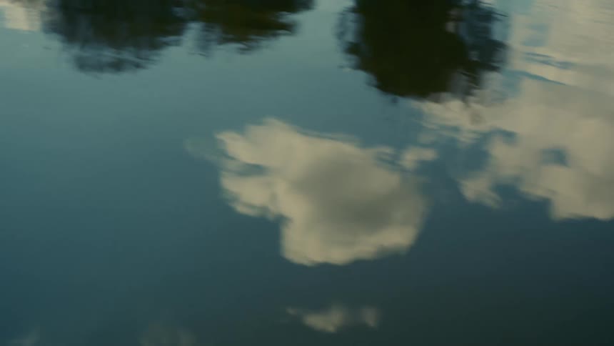 Reflection of clouds trees and blue sky from the water