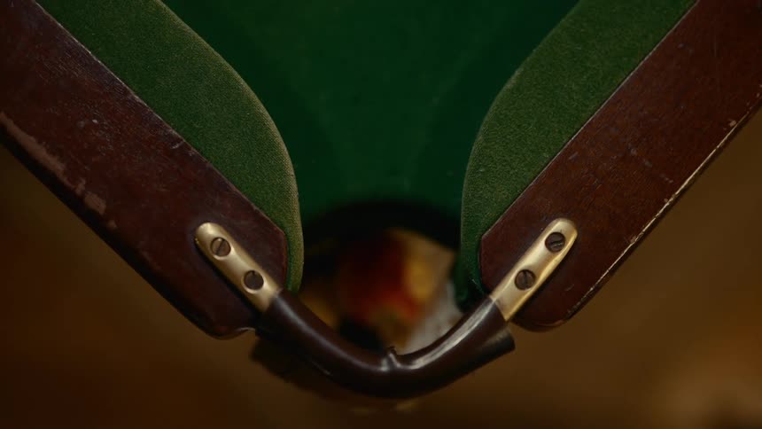 A billiard ball with the number 13 rolls into the corner pocket of a pool table