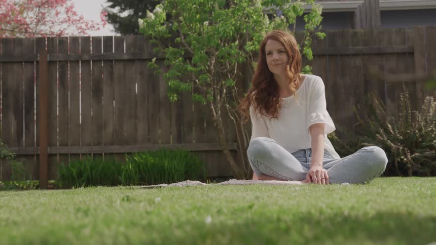 Woman sitting on the grass in a backyard thinking