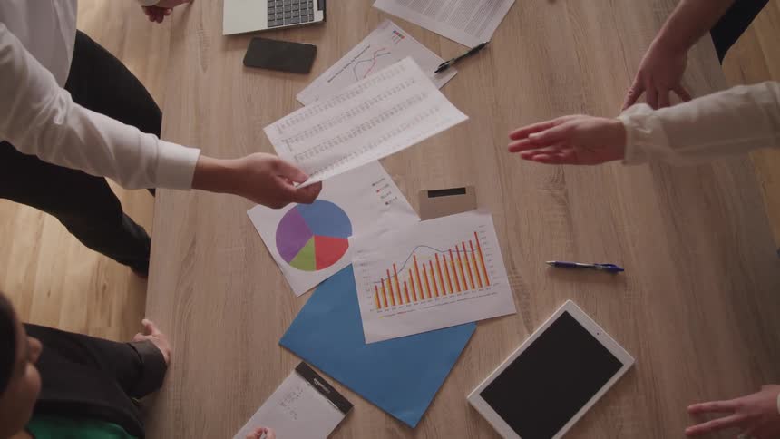 Hands on an office desk with a document being handed to another