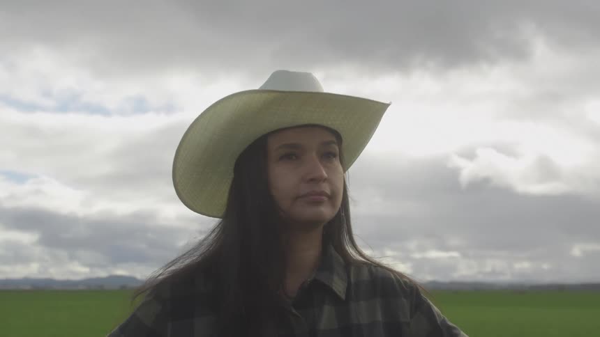 A footage of a lady standing on a green field