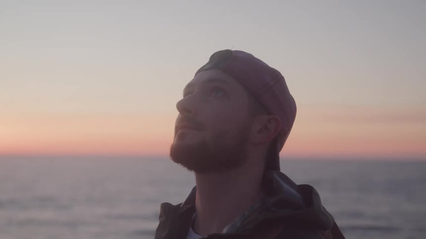 Man in cap looks up enjoying seaside view