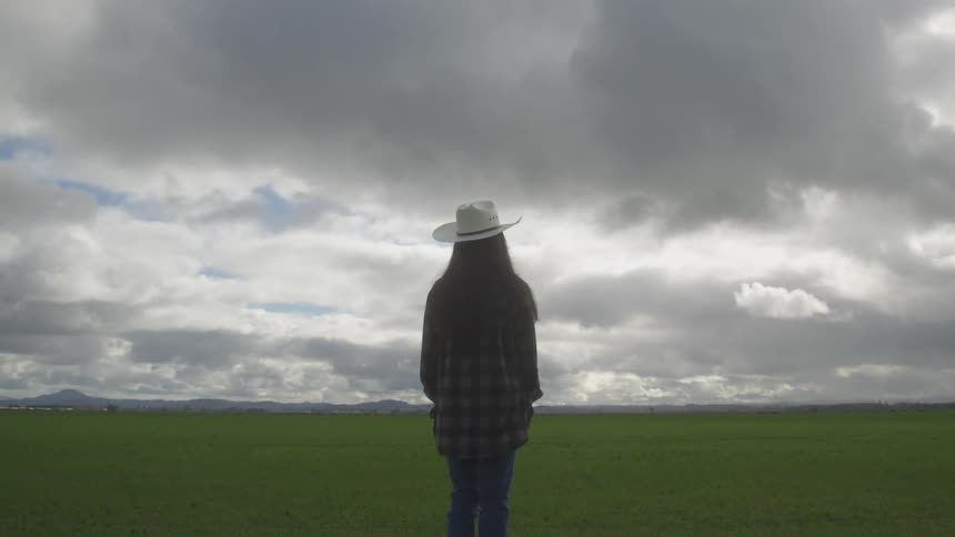 A footage of a person standing on the plain grass filed