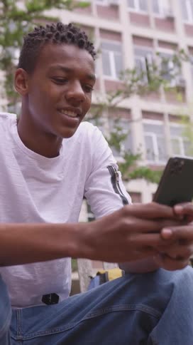 A teenager is texting on his phone outside