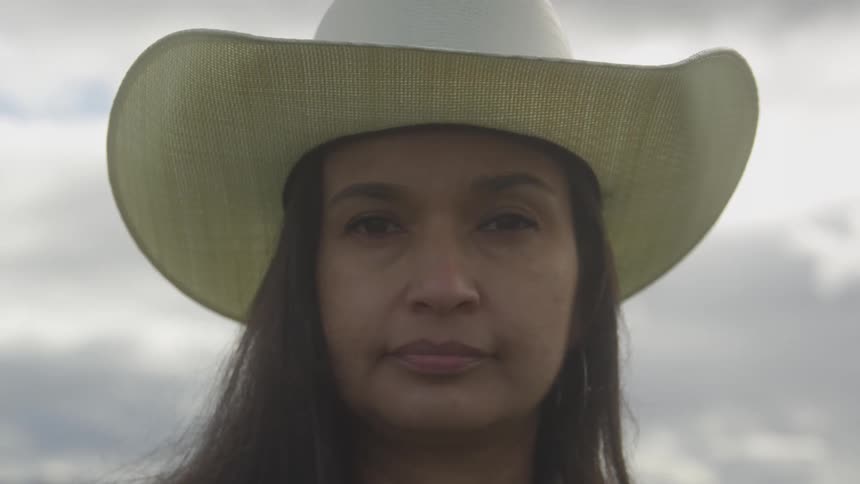 Portrait of a woman outdoors on a cloudy day wearing a cowgirl hat