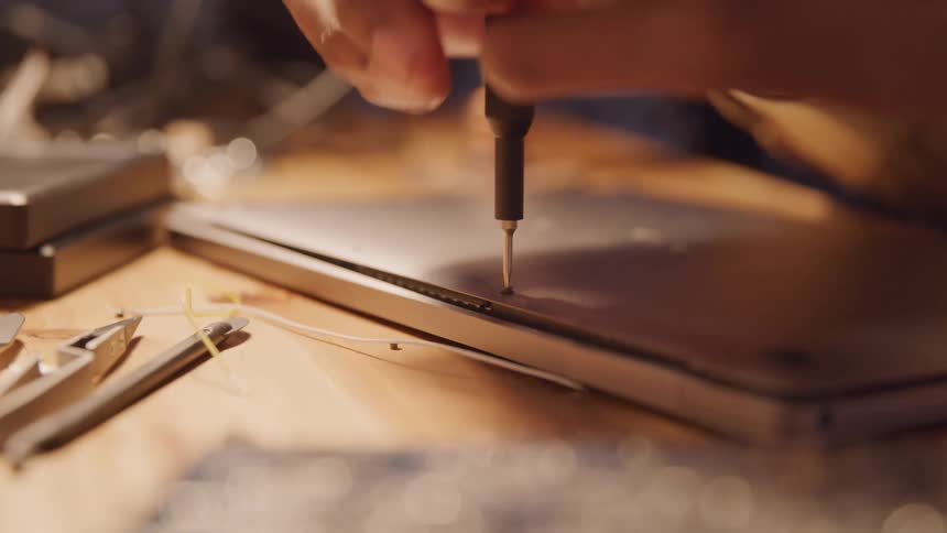 Closeup of an adult removing a screw from the back of an electronic tablet
