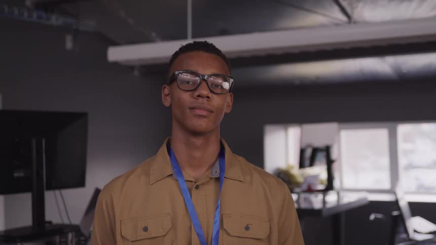 Portrait of a young man in an indoor workspace with glasses