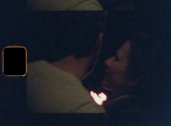 Woman kisses man while they play with sparklers outside at night