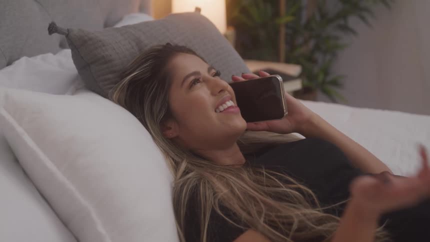 A footage of a woman having a phone conversation on the bed