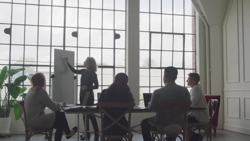 A woman is leading a meeting of a group of people