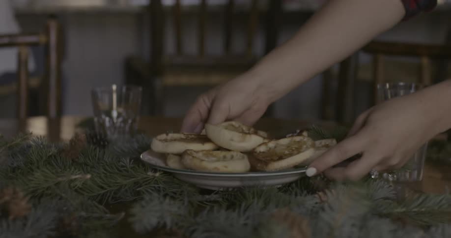 A person placing a plate of food on a table that has a wreath on it
