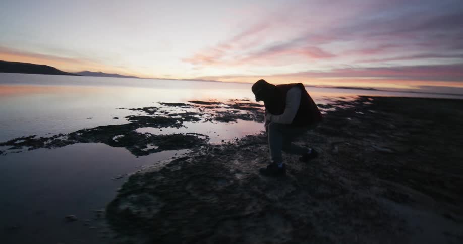 A man is dancing close to the water of a coastal area