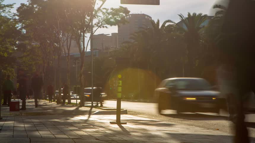 An urban region with a street with many cars passing by and a sidewalk with several pieces moving quickly