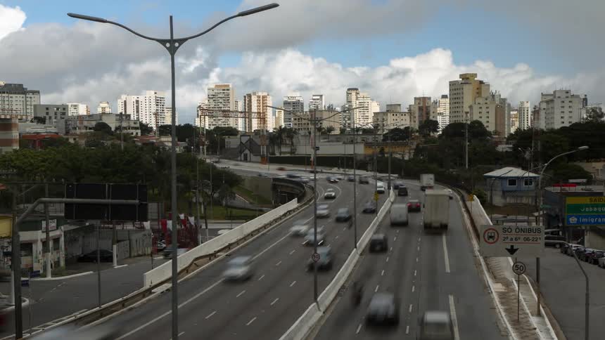 A highway filled with cars stretches into the distance leading towards a cityscape under a cloudy sky