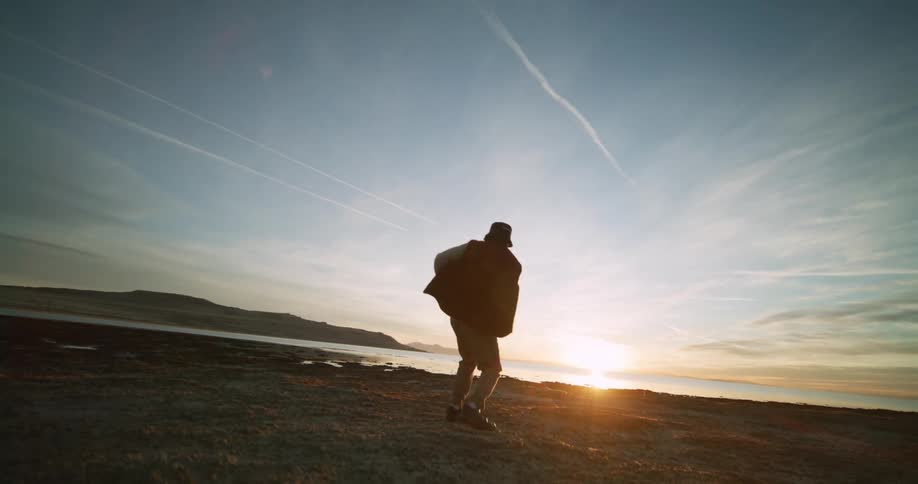 Aerial view of a man dancing by a lake at sunrise