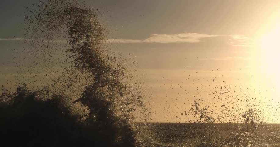 A wave sprays up droplets of water as it breaks