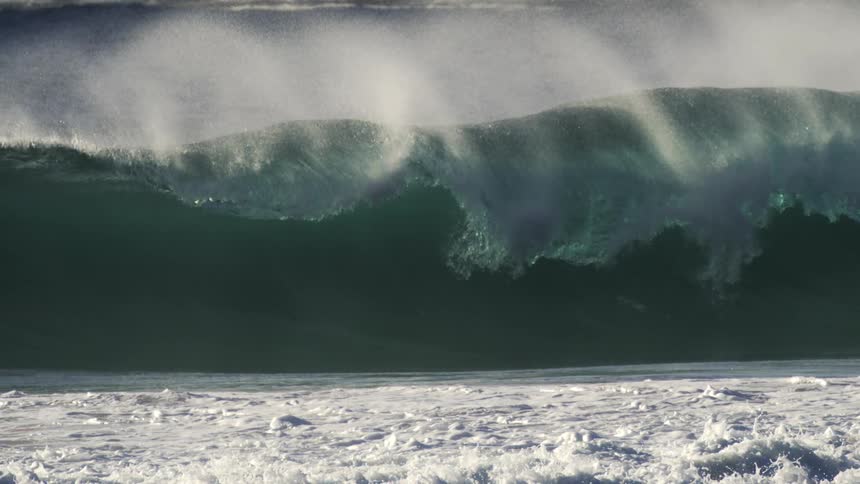 A large waves rolls and crashes on the shore