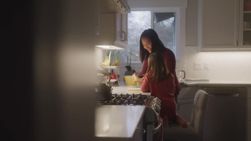 A mother peels a banana for her daughter in a cozy kitchen at home