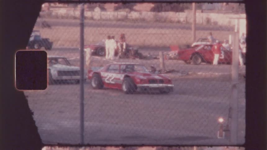Vintage footage of people hanging out around some racing cars on a summer day