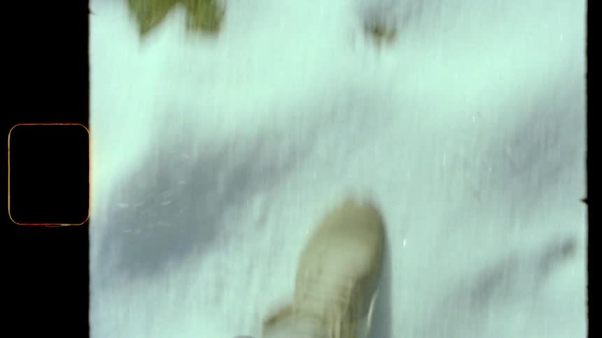 The feet of a person wearing beige sneakers and walking on snowwhite ground