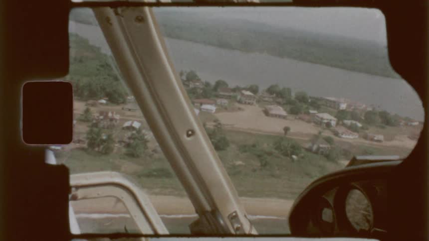 A plane is flying over a town on a river