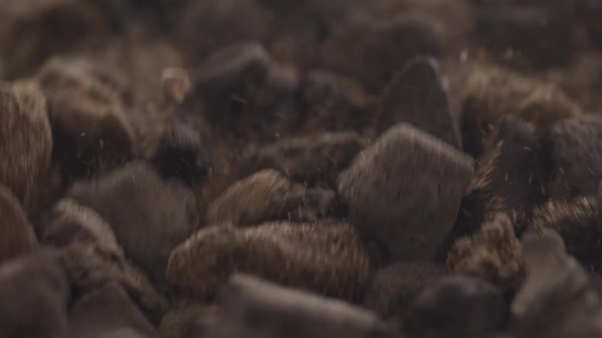 Close up of small stones skipping across abstract sand