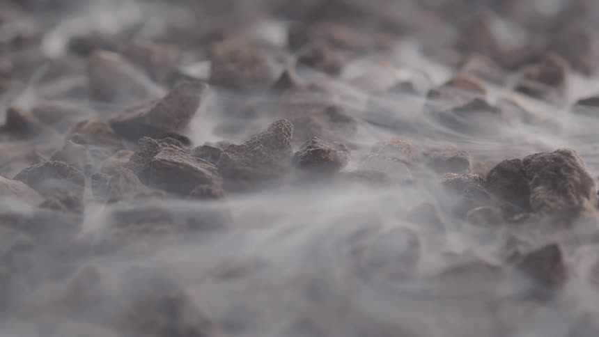 Fog rolls over several stones on the ground