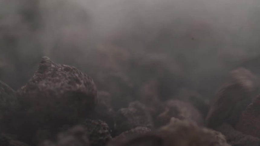Close up of rocks bouncing on a surface amid a cloud of dust