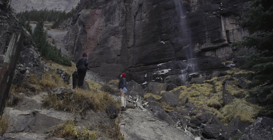 Two people are up on a hill looking up at a mountain