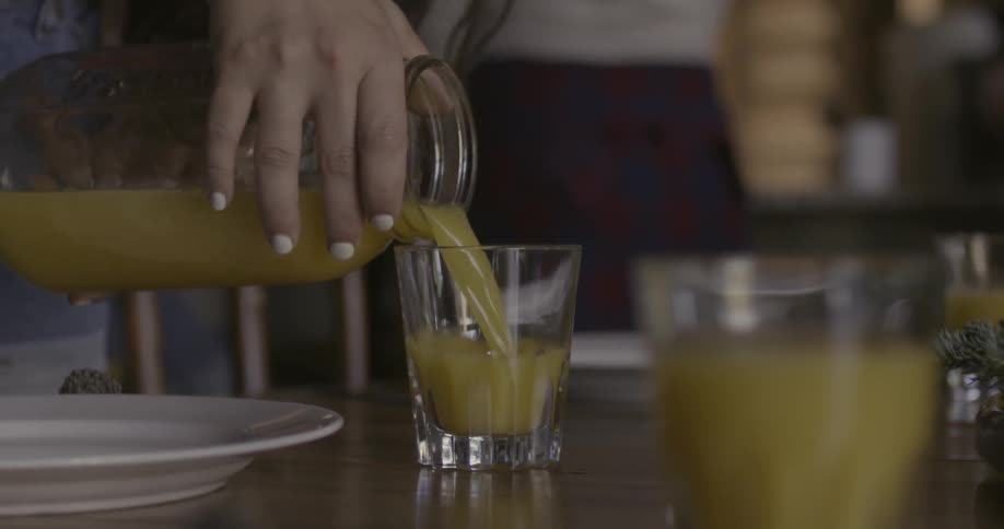 Person pours orange juice into a glass