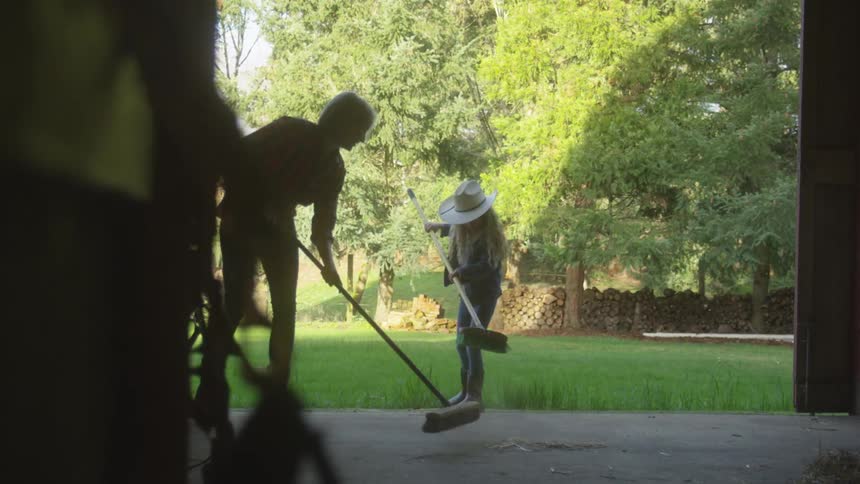 Two farmers are sweeping the barn