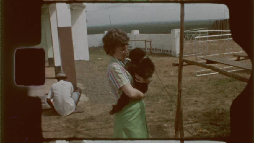 A woman holding a chimpanzee in her arms captured on vintage film