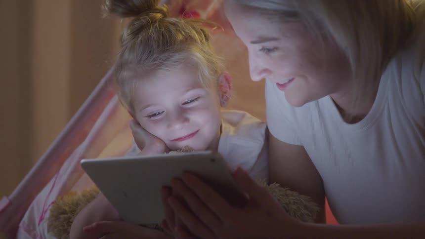 Smiling mother and daughter interacting with a tablet