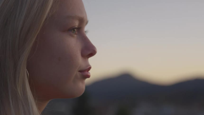 Side portrait of a young blonde woman in a natural outdoor setting