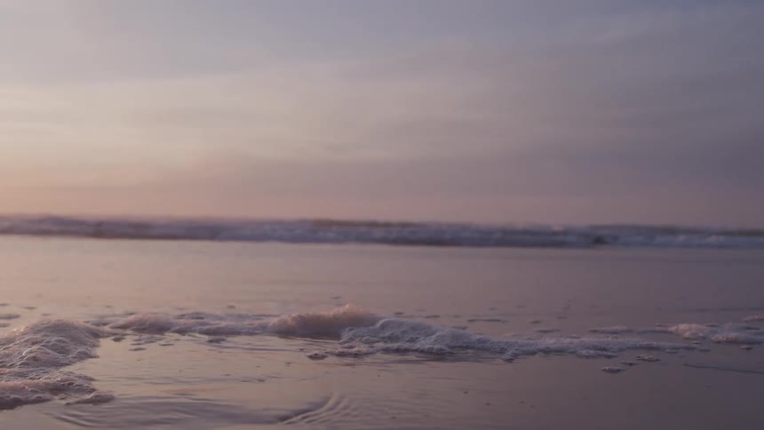 Landscape of a beach with calm waters and a purple sky
