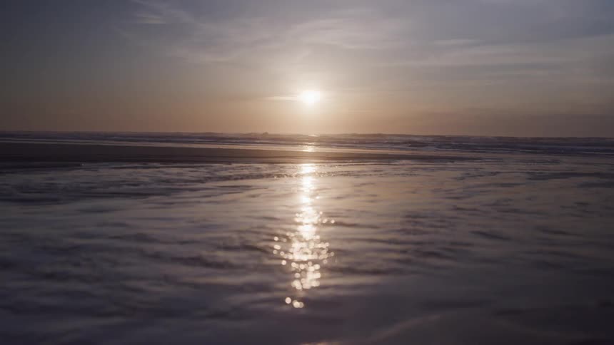 Reflection of the sun on a horizon reflecting in the calm waters of a beach