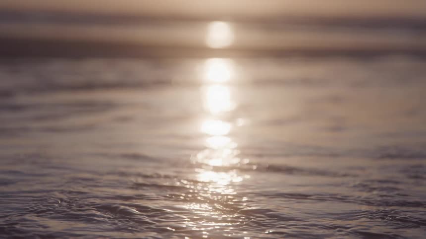 Reflection of the sun in fluid waters on the beach sand
