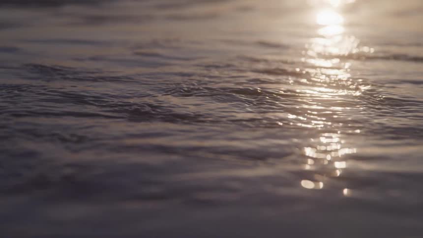 The suns reflection glistens on gently moving water creating a serene atmosphere