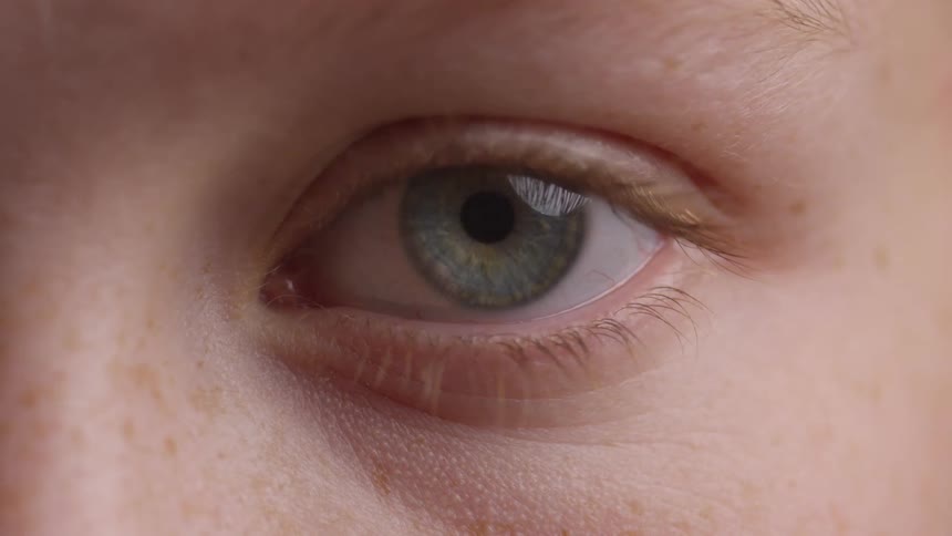 Extreme close up of a blueeyed womans eye opening