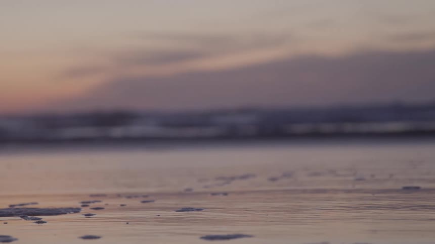 A sandy beach with gentle waves and a pastel sunset sky creates a peaceful atmosphere