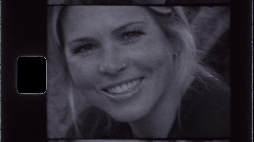 A womans face that is smiling showing her teeth and she is staring straight ahead and everything is in all blacks and whites