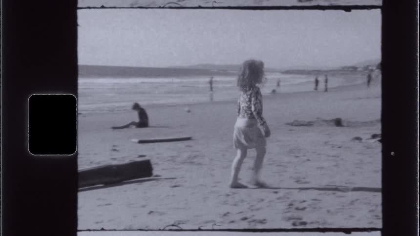 Curly haired child walking on the sand at the beach