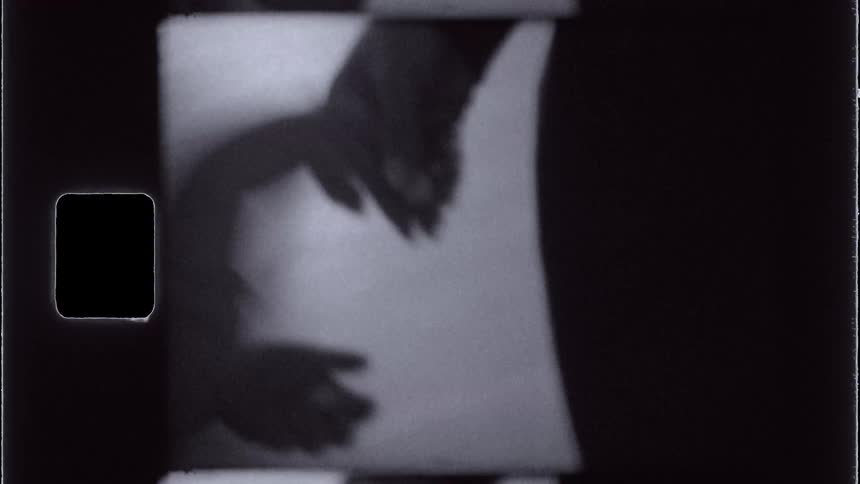 A grainy blackandwhite closeup of an adults hand gently holding a childs hand